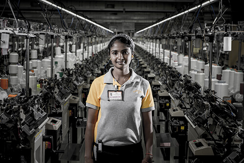 Eine Frau vor den Strickmaschinen in einer Fabrik von ATG.